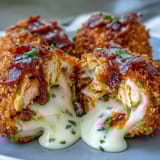 Freshly fried Buffalo Chicken Bacon Mozzarella Bombs bursting with gooey melted mozzarella and crumbled bacon on a white plate.