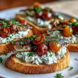 Savory creamy tomato sardine toasts garnished with fresh parsley and cracked pepper.