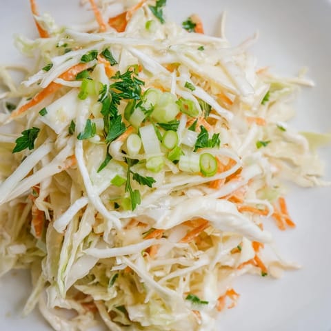 A chilled bowl of Coleslaw with Apple, ready to serve alongside grilled chicken or pulled pork at a summer cookout.