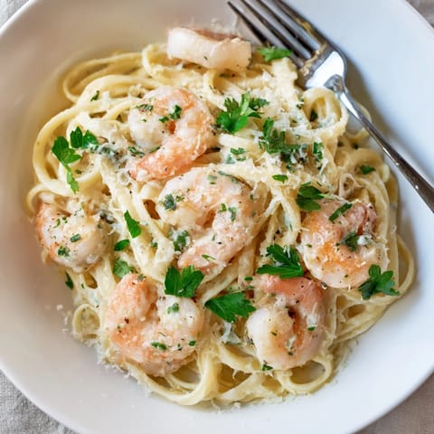 Savory Creamy Garlic Shrimp Pasta is plated with fresh parsley and lemon wedges for a bright, zesty finish.  