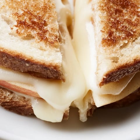 Golden-brown sourdough slices stuffed with melted smoked Gouda and thin apple slices, ready to serve.