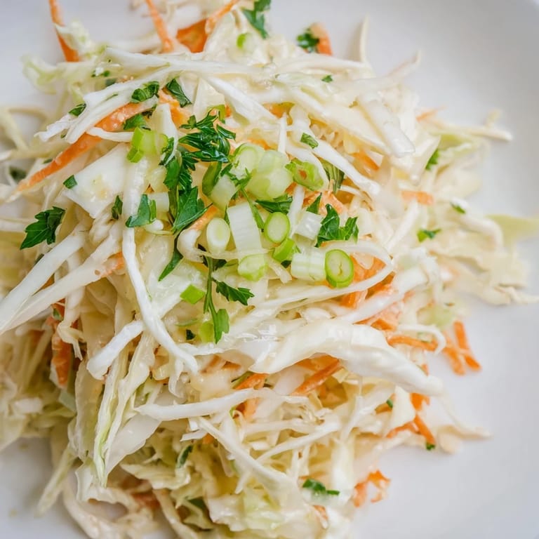 A chilled bowl of Coleslaw with Apple, ready to serve alongside grilled chicken or pulled pork at a summer cookout.