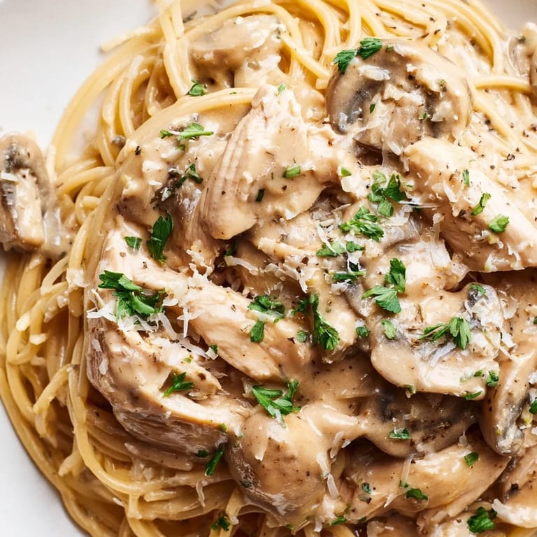 A close-up of Creamy Mushroom Chicken Spaghettini, highlighting golden-brown chicken and a light, creamy mushroom sauce coating every strand.