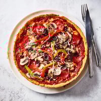 Golden, bubbling Deep Dish Pizza slices reveal a thick, buttery crust layered with molten mozzarella and chunky tomato sauce.