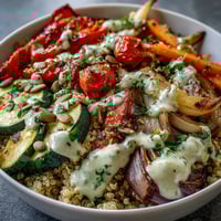 Freshly roasted red bell peppers, zucchini, and carrots sit atop fluffy quinoa in this nourishing Roasted Vegetable Quinoa Bowl, ready for a wholesome vegan dinner.