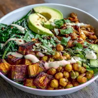 Golden roasted sweet potatoes and crispy chickpeas mounded in a white bowl.