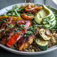 Golden pan-fried chicken and smoky paprika roasted vegetables fill a bowl over fluffy quinoa.