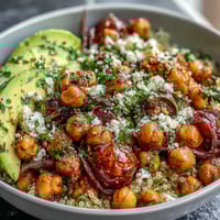 Vibrant lemon vinaigrette grain bowls with roasted chickpeas, fresh vegetables, and avocado slices for a healthy, plant-based meal.  